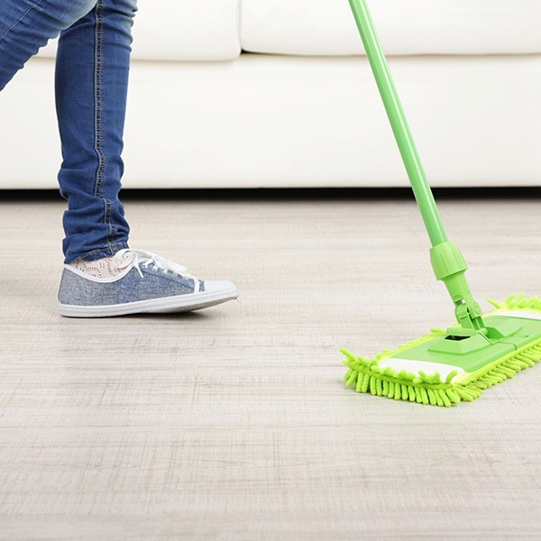 Woman with mop cleaning wooden floor from dust | Direct Flooring Center
